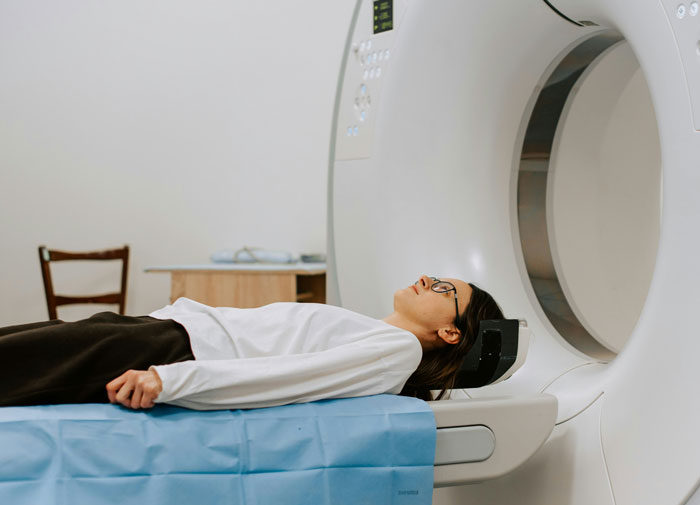 Woman lying on a hospital scanner undergoing a medical imaging procedure related to tumor diagnosis and health evaluation.