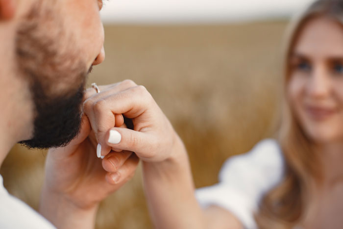 Man holding woman's hand tenderly in a field, conveying deep regret after ditching fianc&eacute;e to chase one that got away.