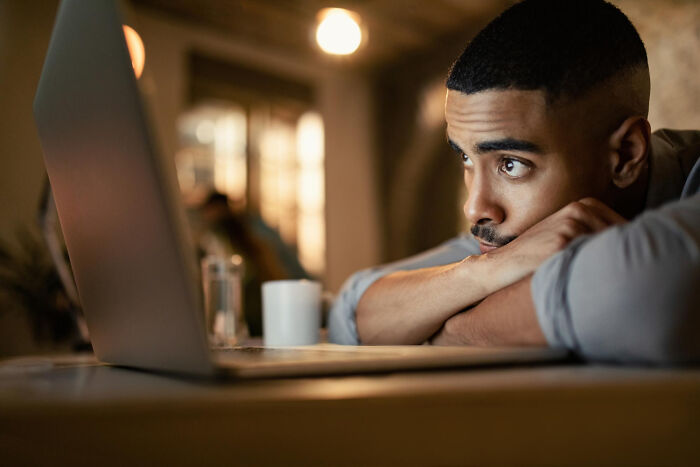 Man with focused expression looking at laptop screen, illustrating karma hitting people trying to sabotage others.