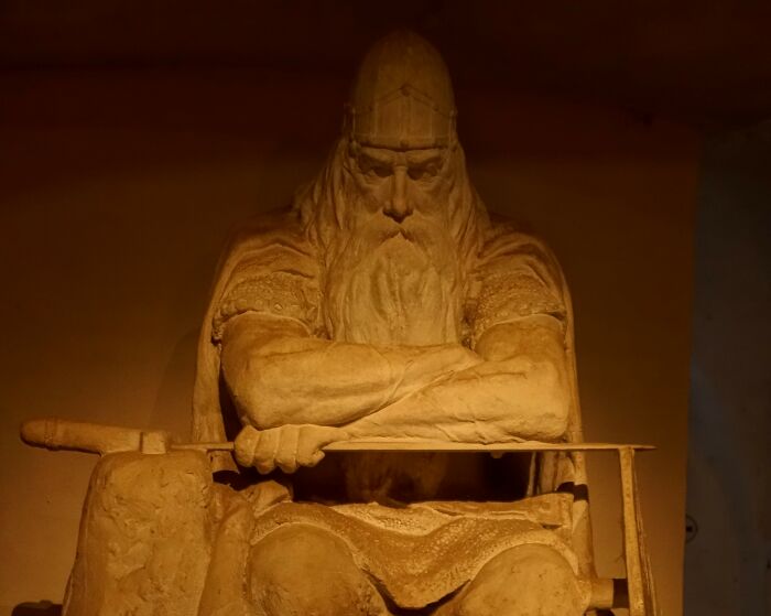 Stone statue of a bearded warrior with a sword, representing iconic landmarks and popular myths around the world.