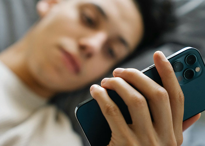 Person lying down, holding a smartphone, reflecting on moments their ex revealed who they really were.