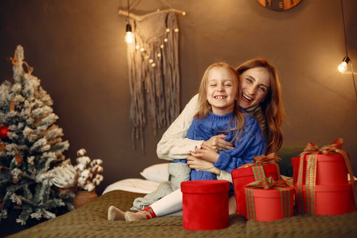 Mother and child smiling together in a cozy room with wrapped gifts, evoking thought-provoking ethical and moral dilemmas.