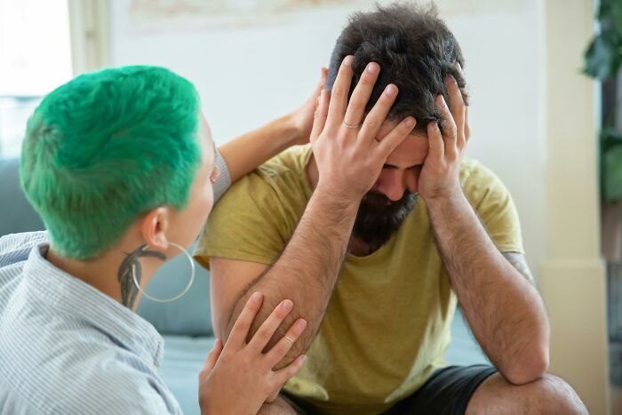 Person with green hair comforting a distressed man, illustrating thought-provoking ethical and moral dilemmas in a casual setting.
