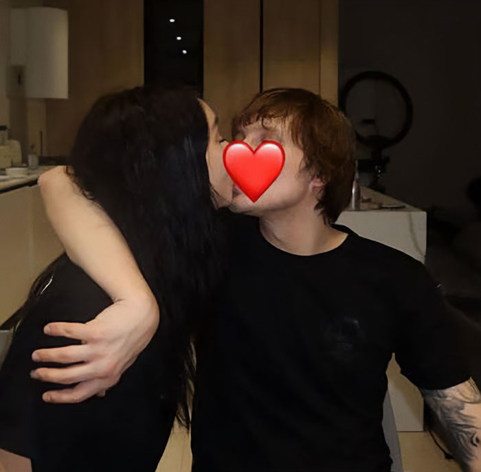 Young couple sharing a kiss indoors with a heart emoji covering their faces, related to a horrifying discovery in Bali ransom case.