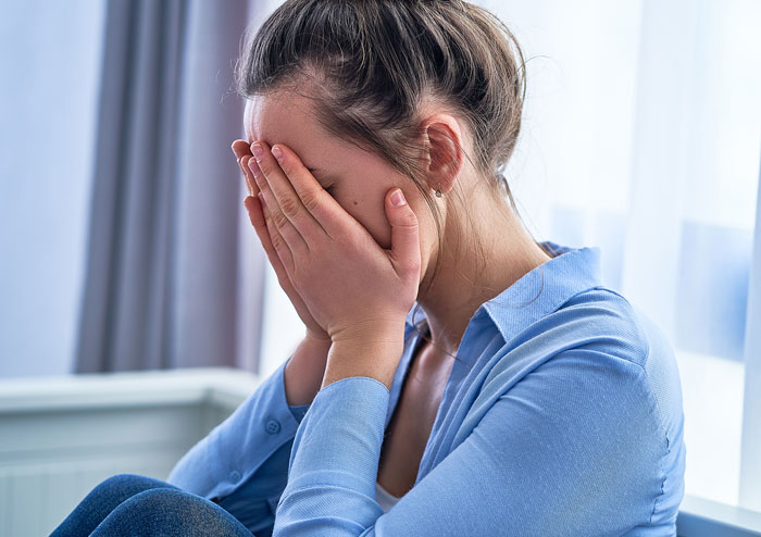 Woman in blue shirt crying and covering her face, upset about neighbors and cat theft involving her sheriff dad.