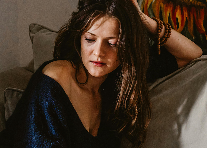 Young woman looking down with worried expression, symbolizing a cheater hiding a one night stand secret at home.