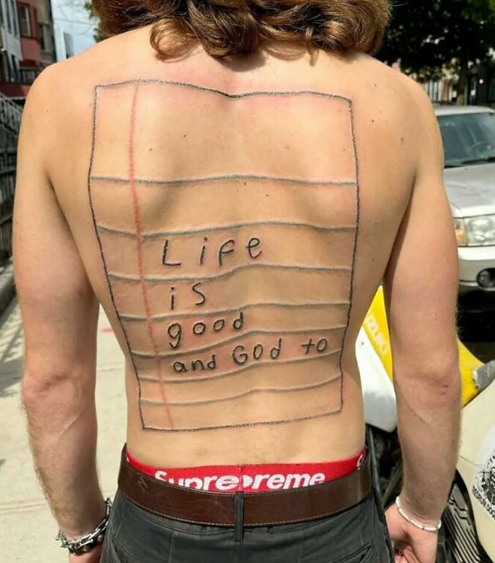 Back tattoo resembling a lined paper with handwritten text, an example of ink fails and bad tattoo ideas.