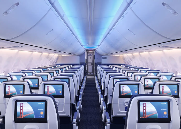 Interior view of a major airline cabin showcasing new passenger seating and in-flight entertainment screens.