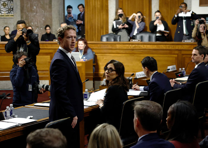 Mark Zuckerberg at a hearing, surrounded by people and cameras, addressing concerns about users' smart glasses privacy.