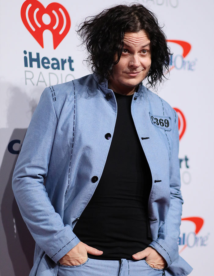 Jack White posing at iHeartRadio event, wearing a light blue jacket and black shirt, addressing recent backlash and response.