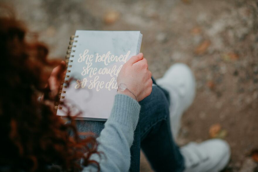 Person holding a notebook with motivational quote outdoors, illustrating practical psychology tricks in everyday life situations.