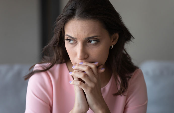Worried woman in pink shirt reflecting on family conflict after catching mom with her fiancé, facing emotional distress.