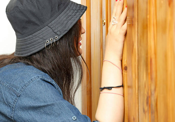 Woman leaning against wooden door with regret after man falls into deep regret chasing one that got away.