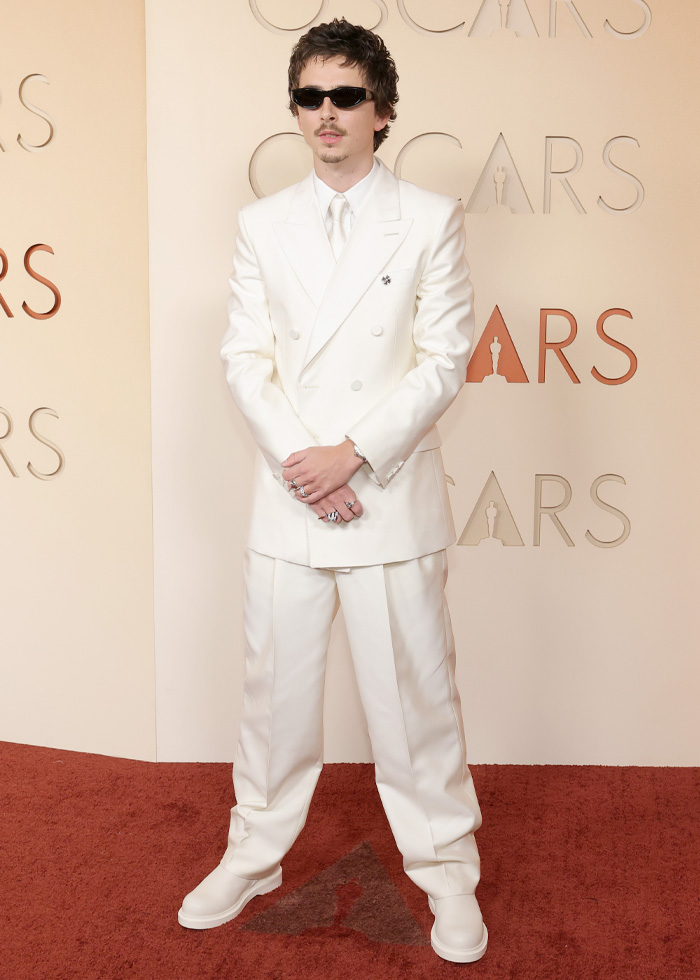 Man wearing a stylish all-white suit and sunglasses on the red carpet showcasing jaw-dropping outfits from Oscars 2026 event.
