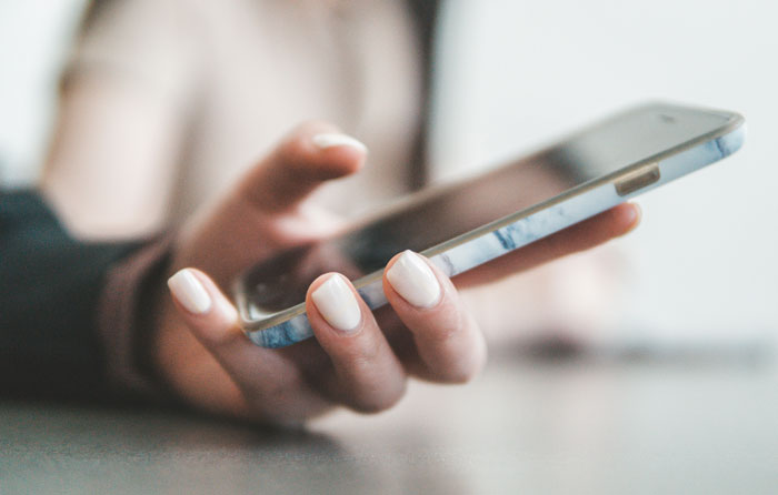 Close-up of woman’s hand holding a smartphone, symbolizing tension after cutting off parents over fiancé betrayal.