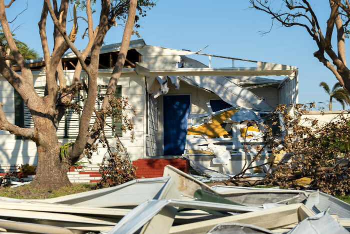 Damaged house with broken porch and fallen tree branches, showing the effects of karma after a sabotage attempt.