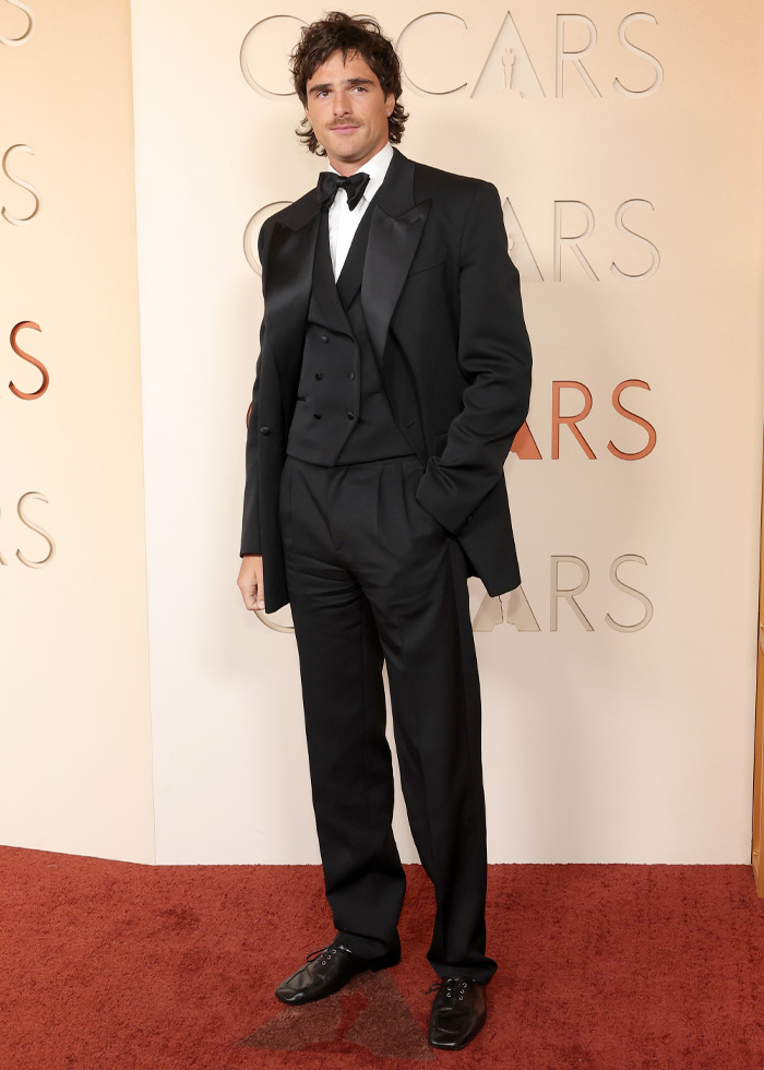 Man in a black tuxedo posing on the red carpet showcasing jaw-dropping outfits from Oscars 2026 that left fans speechless.