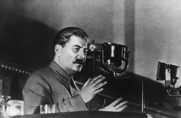 Historical black and white photo of a Joseph Stalin speaking at a microphone, representing leaders who changed history.