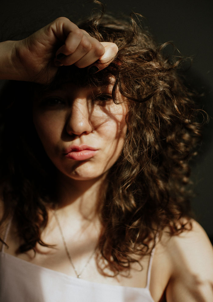 Woman with curly hair looking frustrated, representing bride furious over sister’s workout and appearance at wedding. Woman with curly hair looking frustrated, representing bride furious over sister’s workout and appearance at wedding.