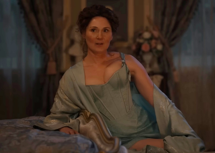 Ruth Gemmell in Bridgerton costume sitting on a bed in a dimly lit room during an intimate sequence filming.