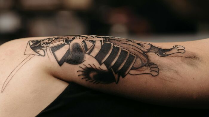 Tattooed arm with a black ink design highlighting the impact of peer pressure.