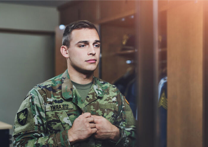 Young soldier in US Army uniform preparing in front of a mirror, reflecting on spine-chilling experiences in haunted places.