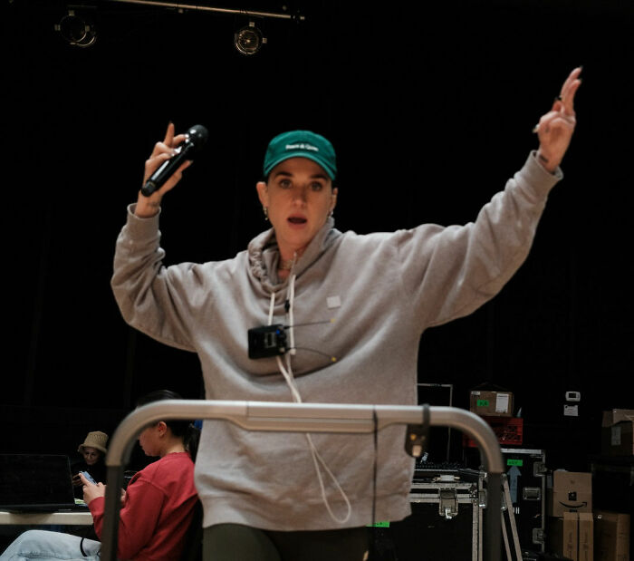 Katy Perry in casual wear holding microphone during rehearsal, linked to grim response and fan struggles controversy.