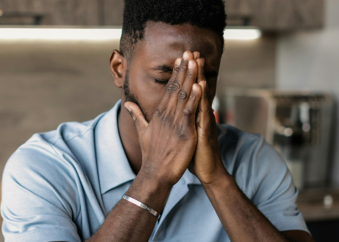 Stressed man covering face with hands, reflecting on cheating, secret one night stand, and threat from a friend.