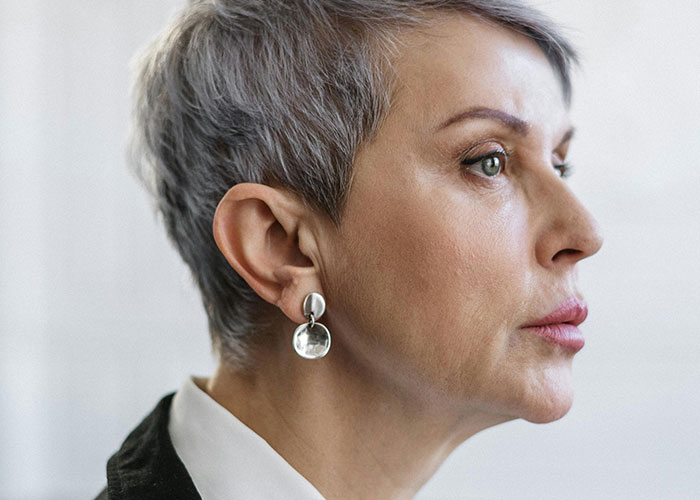 Woman with short gray hair and silver earrings looking worried, representing concern about man caring for his baby at 4 AM