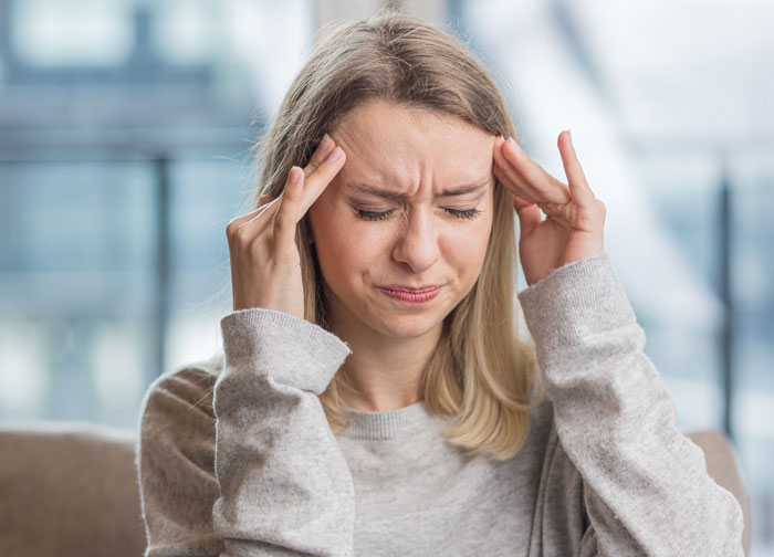 Woman furious and stressed, holding her head, upset about sharing a room during vacation with friends.