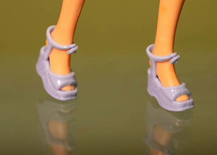 Close-up of doll feet wearing purple sandals, illustrating unserious reasons people ended up in ER from tripping accidents.