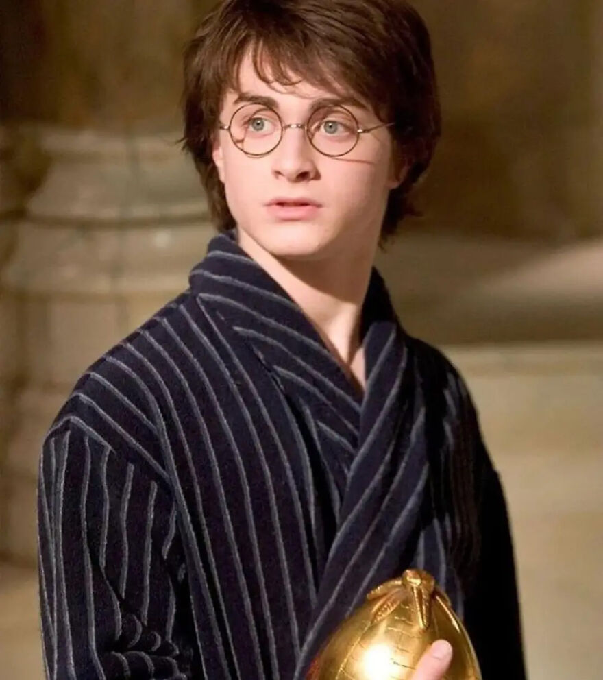 Daniel Radcliffe with green eyes wearing round glasses and a striped robe holding a golden object indoors, highlighting rare green eyes genetics. Daniel Radcliffe with green eyes wearing round glasses and a striped robe holding a golden object indoors, highlighting rare green eyes genetics.