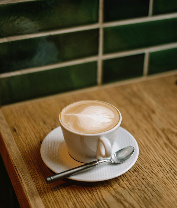 A cup of coffee with latte art on a wooden table, representing harmless secrets shared between partners.