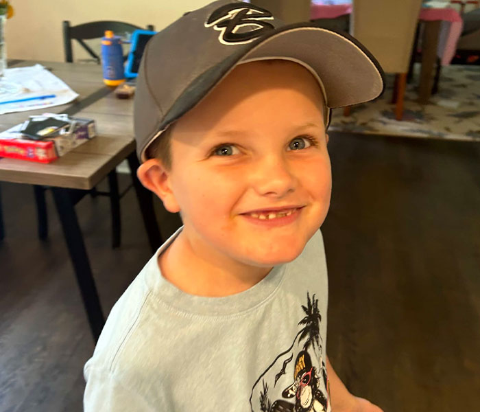 Smiling young boy wearing a baseball cap indoors, representing bizarre medical problems and mysteries in the news.