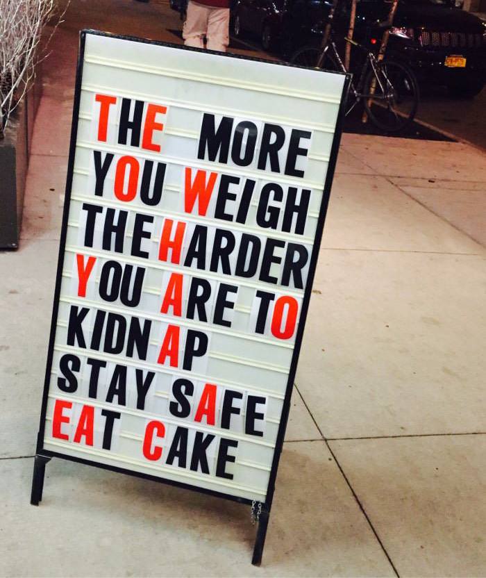 Funny pieces of advice on a sidewalk sign suggesting eating cake to stay safe from kidnappers, humorous street sign.