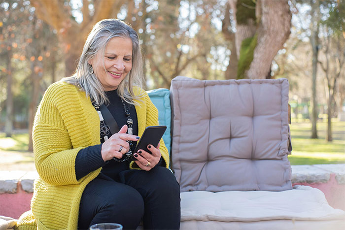 Woman sitting outdoors using smartphone, representing HR dumbfounded when employee refuses to train a new employee for free. Woman sitting outdoors using smartphone, representing HR dumbfounded when employee refuses to train a new employee for free.