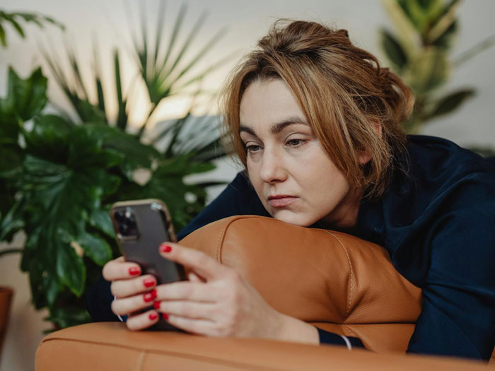 Woman with concerned expression lying on couch, staring at phone, suspecting husband is a psychopath after texts. Woman with concerned expression lying on couch, staring at phone, suspecting husband is a psychopath after texts.