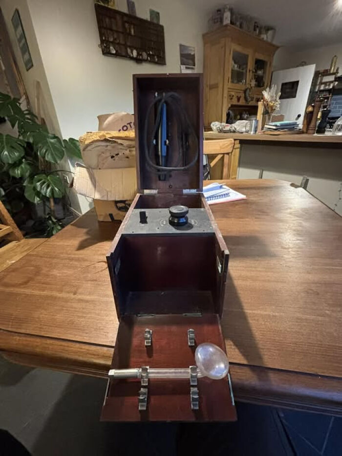 Antique wooden device with a glass bulb and metal parts displayed on a table, internet solved mystery of unidentified objects.