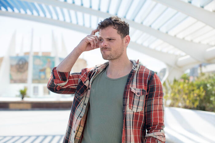Man in plaid shirt looking confused outdoors, representing creepy advances and amazing women shut down moments.