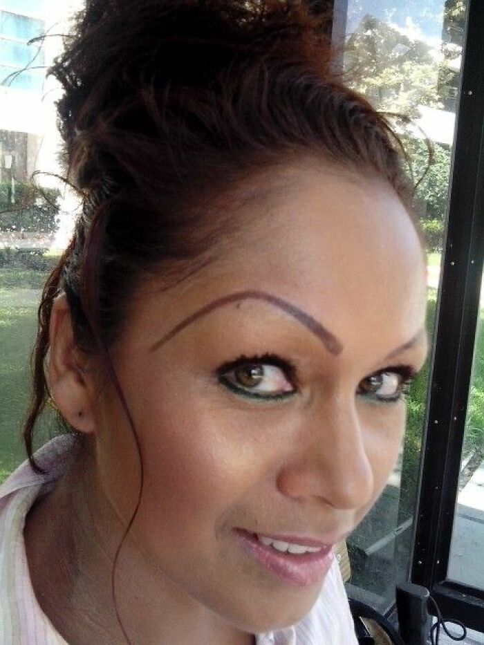 Woman with unusually shaped, crooked eyebrows creating a crazy eyebrow effect on her face with playful expression.