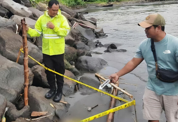 Two men at a rocky riverbank examining a section cordoned off with yellow tape during a horrifying discovery in Bali.