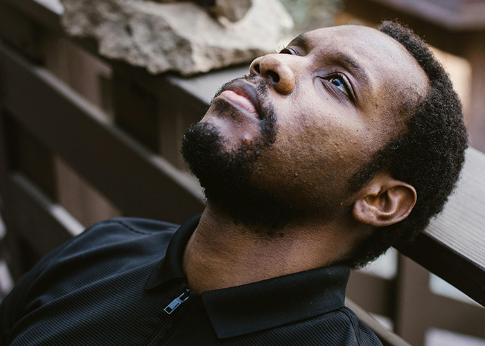 Man with contemplative expression leaning back on a bench, reflecting on a cheater hiding a one night stand secret.