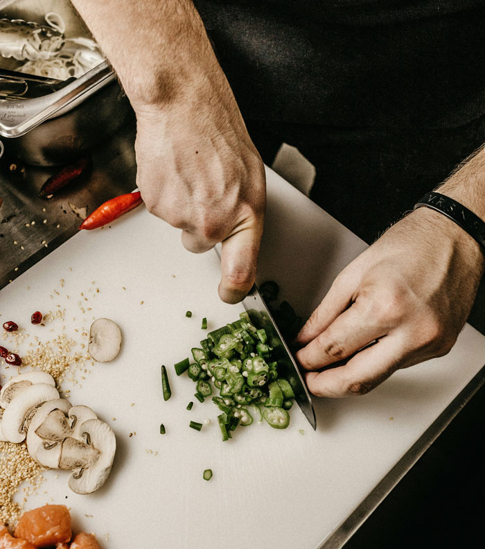 As mãos do homem cortando legumes em um quadro branco simbolizando um marido lidando com o comentário cruel da esposa grávida. As mãos do homem cortando legumes em um quadro branco simbolizando um marido lidando com o comentário cruel da esposa grávida.