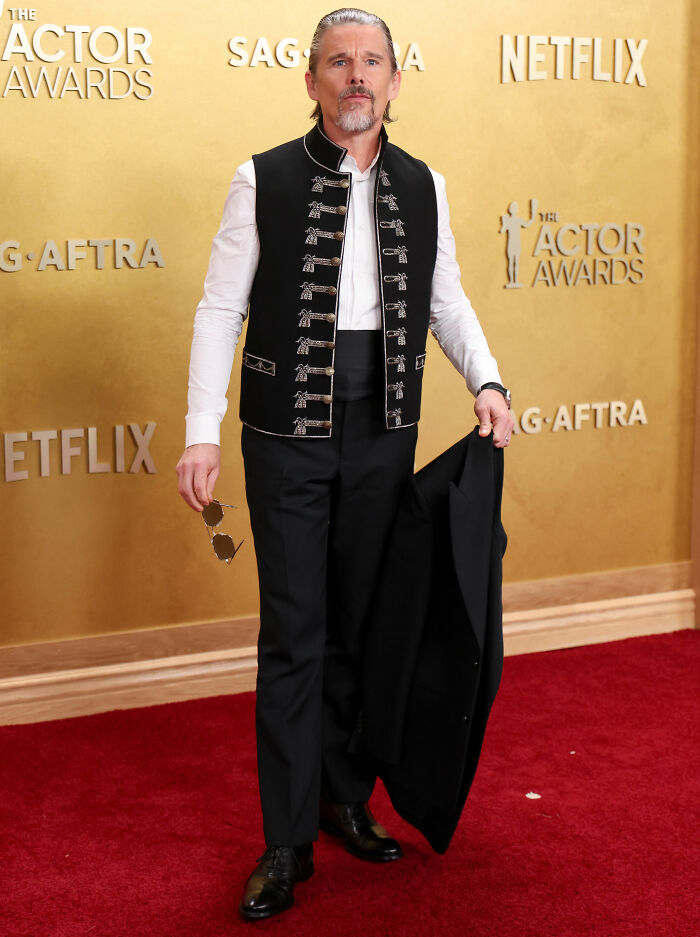 Male celebrity on red carpet at Actor Awards, dressed in black and white outfit, example of worst dressed stars style fatigue.