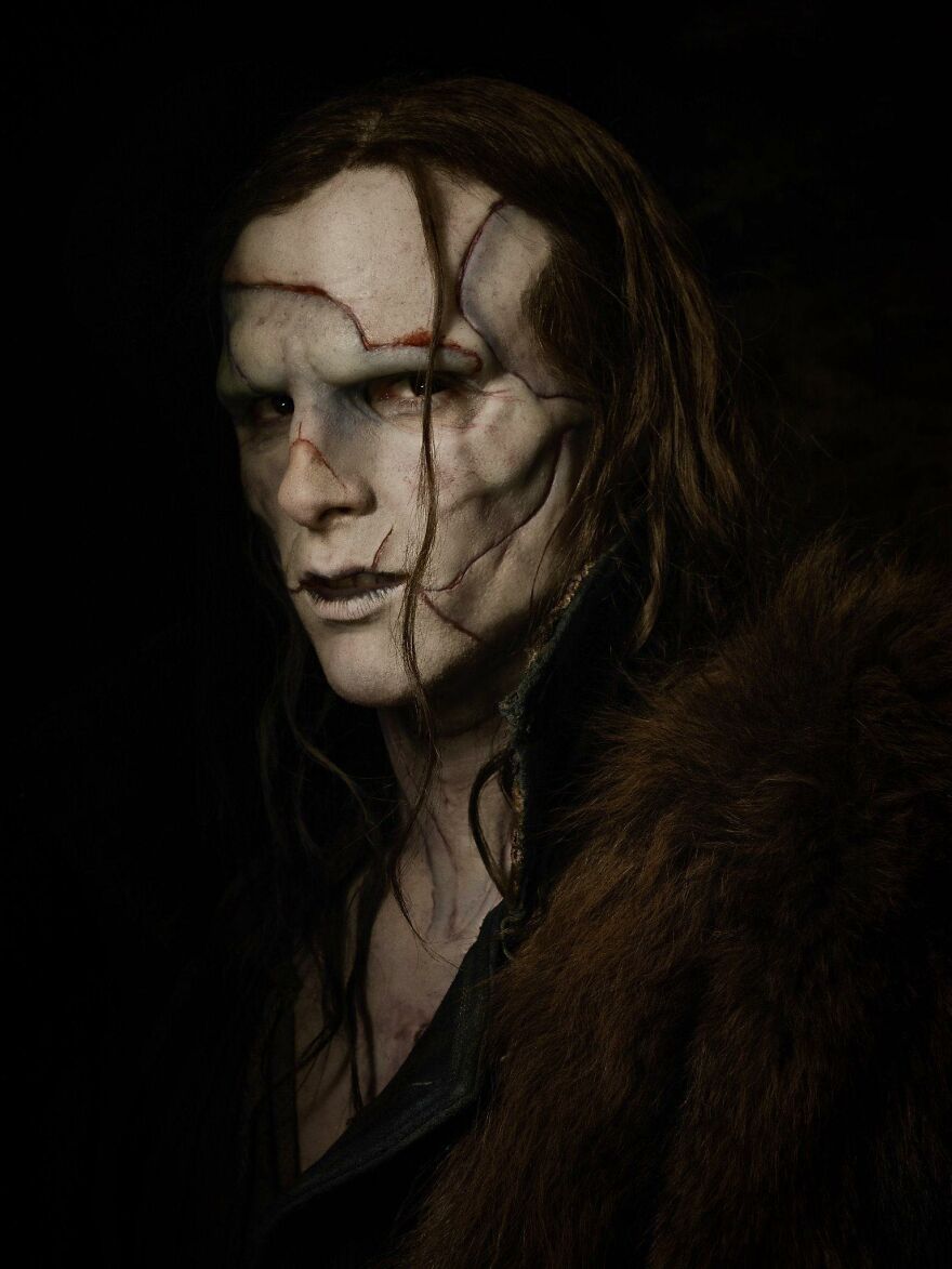 A supporting performance featuring a character with detailed prosthetic makeup and scars in a dark, dramatic setting.