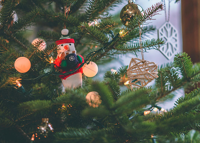 Festive Christmas tree decorated with lights, ornaments, and a small snowman highlighting unserious reasons for ER visits.