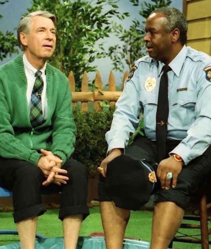 Two men sitting outdoors in a small pool, sharing a lighthearted moment, representing uplifting posts about good in the world.