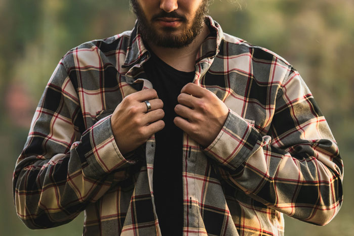 Man in a plaid shirt buttoning up outdoors, illustrating relationships teaching women about men in unique ways.