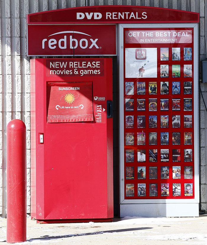 Redbox DVD rental kiosk outside a store displaying new release movies and games with corporate secrets behind the service revealed.