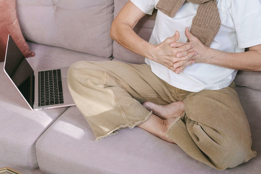 Person sitting cross-legged on a couch with laptop nearby, demonstrating practical psychology tricks for real-world situations.